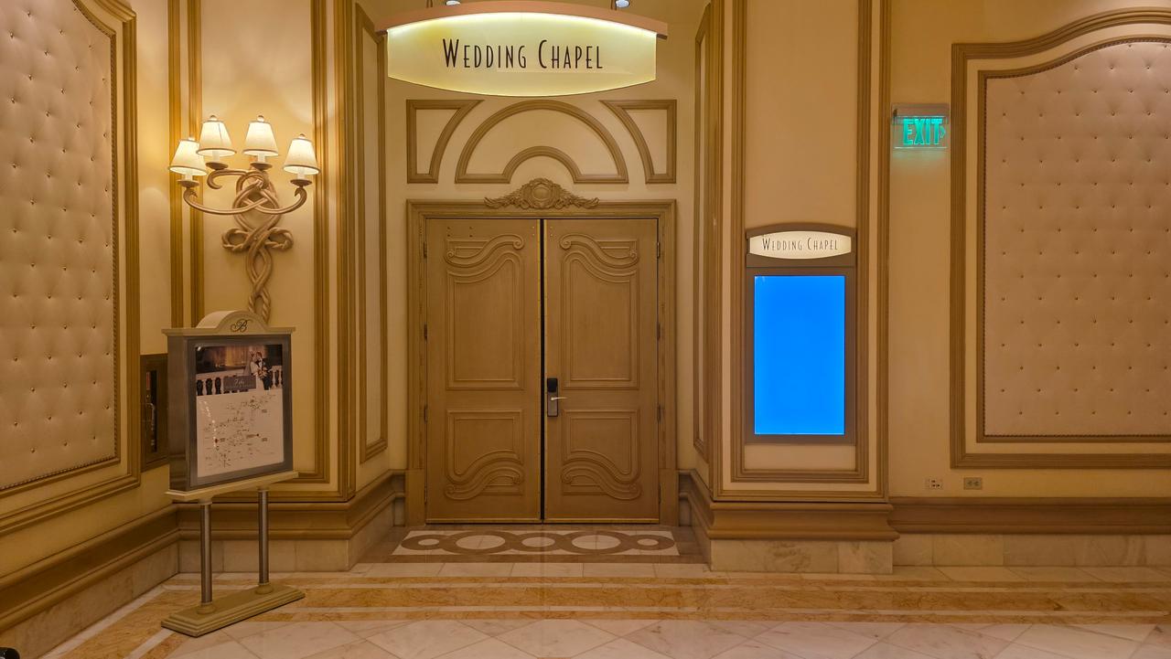 An ornate indoor wedding chapel with stained glass windows, cream-colored seating, and floral arrangements.