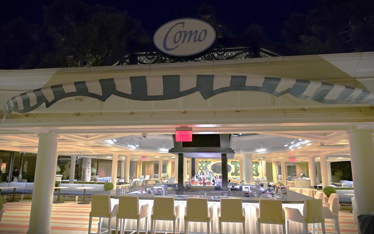 The outdoor dining terrace at COMO Poolside Café and Bar featuring white umbrellas and tables near the pool deck.